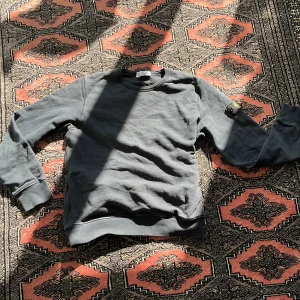 Blå sweatshirt från Stone Island Junior - Säljer en stilren blå sweatshirt från Stone Island Junior. Tröjan har långa ärmar och en klassisk rund halsringning. Den ikoniska Stone Island-loggan sitter på ärmen. Perfekt för en avslappnad look.