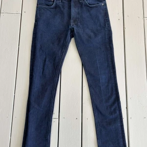 Nudie jeans, Lean Dean i färgen mörkblå - Snygga mörkblå jeans från Nudie Jeans med en klassisk femficksdesign. De har en slim passform och är tillverkade i högkvalitativt denim. Perfekta för en stilren look. Prist är inte gjutet i sten så hör gärna av er!