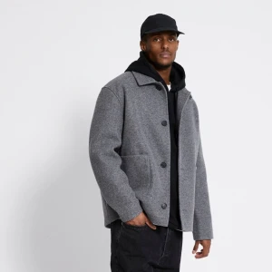 Grå ulljacka med knappar - Snygg grå ulljacka med klassisk krage och knäppning framtill. Jackan har en stilren design med stora fickor och är perfekt för kyligare dagar. Passar bra till både vardag och mer uppklädda tillfällen.