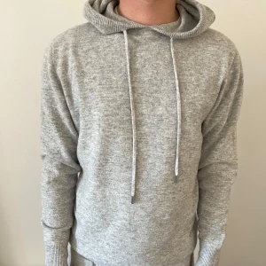 Grå merino och kasmir hoodie - Säljer en stilren och helt oanvänd grå hoodie med merino och kashmirblandning. Bara att höra av sig vid frågor!