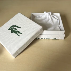 Silverfärgat armband från Lacoste - Säljer ett stilrent silverfärgat armband från Lacoste. Armbandet kommer i en elegant vit förvaringspåse med dragsko och en matchande presentask. Perfekt som accessoar för att komplettera din look. Nypris 1000kr 