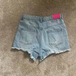 Ljusa jeansshorts med fransar - Snygga ljusa jeansshorts, med fransiga kanter och slitna detaljer. Perfekta för en avslappnad sommarlook. De har en klassisk femficksdesign och knappgylf.