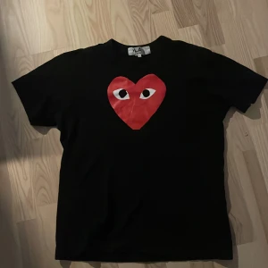 Svart t-shirt från Comme des Garçons Play - Säljer nu min cdg play tisha! Storlek L men sitter som M passar också s skulle jag säga! Lite sliten på hjärtat men inga andra defekter! 