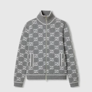 Grå stickad cardigan jacka från Gucci - Grå stickad cardigan jacka från Gucci med hel dragkedja och hög krage. Jackan har ett vitt GG-mönster över hela plagget och ribbade muddar vid ärmslut, nederkant och krage. Två fickor framtill med vita detaljer ger en clean look.