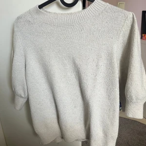 Stickad kortärmad tröja  - Säljer en stickad tröja från Vero Moda. Den har använts några gånger men kommer inte till användning längre. Kontakta vid frågor. Den är fortfarande vit men inte lika som innan. Köpt för 250-300kr