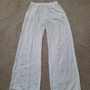 Vita linnebyxor från Mix, storlek 158/164 - Snygga och luftiga vita linnebyxor från Mix med resår och snörning i midjan. Byxorna har raka, vida ben och sidfickor, perfekta för en chill och avslappnad stil. Passar dig som gillar bekväma och stilrena plagg.
