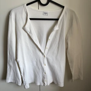 Vit kofta från Filippa K i bomull - En stilren vit kofta från Filippa K i mjuk bomull. Koftan har trekvarts ärm, knappar framtill och en enkel, klassisk design. Köpt begangnad men användes knappt. Pris kan diskuteras.