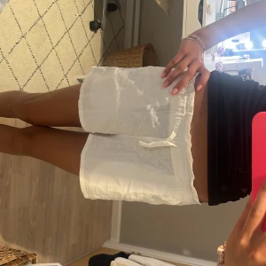 Vita linneshorts med snörning - Säljer ett par vita shorts i linne med elastisk midja och snörning framtill. perfekta för varma sommardagar. Stilen är enkel och fräsch, med mjukt och svalt material.