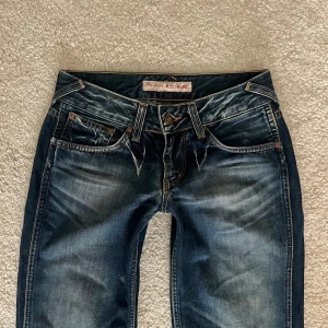 Lågmidjade Pepe Jeans - Lågmidjade utsvängda jeans från Pepe Jeans i storlek XS/S. Midjemåttet är 34cm tvärsöver och innerbenslängden är 77cm.  Har en fläck (se sista bild) men annars gott skick!!