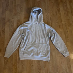 Beige hoodie från FSBN, relaxed fit - Enkel och stilren beige hoodie från FSBN i relaxed fit. Tröjan har huva, magficka och långa ärmar. Perfekt för chill dagar eller när du vill ha en clean look. Tillverkad i mjuk bomullsmix. 