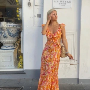 Trendig zara klänning - Superfin långklänning i blommigt mönster med rosa, orange och gula toner. Klänningen har volangdetaljer, v-ringning och är ärmlös med breda axelband. Sval och flowy i linneblandning, perfekt för sommardagar och midsommar. Sömmarna är lite uttöjda (se sista bilderna)💕