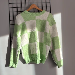 Grönvit rutig stickad tröja - Supermysig stickad tröja med stora gröna och vita rutor. Tröjan har rund hals, ribbade muddar och en loose fit som ger en chill vibe. Perfekt för dig som gillar färg och vill sticka ut lite extra i vardagen.
