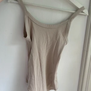 Beige body - Ribbad beige string body från H&M i storlek XS. Aldrig använd. Med knappar vid skrevet.  Allt ska bort kolla mina andra annonser!🌺