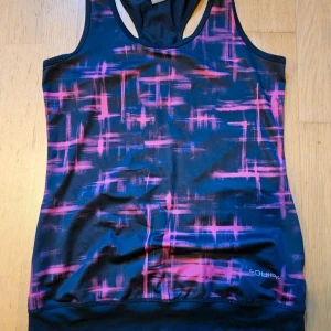 Mönstrad träningstopp från Equipe Sport - Säljer en sportig linnetopp från Equipe Sport i storlek M. Toppen har ett coolt grafiskt mönster i rosa  på mörk botten, med brottarrygg och meshpanel baktill för extra ventilation. Perfekt för träning och aktiva dagar.