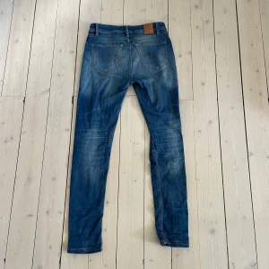 Blå Replay jeans slim fit - Snygga blå jeans från Replay med klassisk femficksdesign och diskreta slitningar. Jeansen har smal passform och raka ben, tillverkade i mjukt bomullstyg med lite stretch. Perfekta för dig som gillar en stilren och avslappnad look.