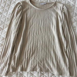 Beige ribbad tröja från Name It - Snygg beige långärmad tröja från Name It med ribbat mönster och smått puffade axlar. Pris går att diskutera☺️