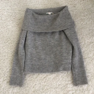 Grå stickad tröja från Gina Tricot - Mysig grå stickad tröja från Gina Tricot med bred, ribbad krage som kan vikas ner. Tröjan har lång ärm och ribbade muddar vid ärmslut och nederkant. Perfekt för kyliga dagar och enkel att matcha med jeans eller en kjol 💞