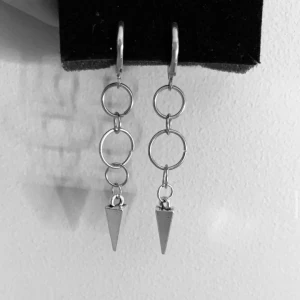 Silvriga örhängen med ringar och koner - Unika silvriga örhängen med tre sammankopplade ringar och en spetsig konformad detalj längst ner. Snyggt minimalistiska och edgy, perfekta för att lyfta din stil.