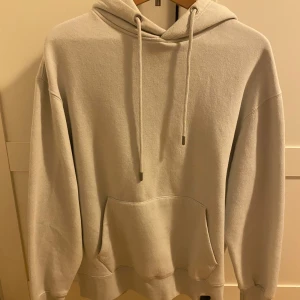 Beige hoodie från Pull&Bear - Säljer en stilren beige hoodie från Pull&Bear i storlek S. Tröjan har huva med snörning, magficka och ribbade muddar. Perfekt för en chill och avslappnad look. Materialet är mjukt och skönt, troligtvis bomullsmix.