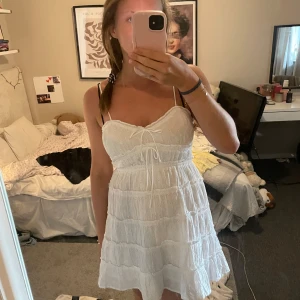 Vit somrig klänning Gina Tricot - Superfin vit kort klänning från Gina Tricot med tunna axelband och volangiga lager. Enbart använd en gång🩷 