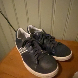 Mörkblå sneakers från Björn Borg - Fina mörkblå sneakers från Björn Borg, går att fås med vita tjocka snören. Inga defekter.