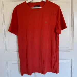 Orange t-shirt från Morris  - Snygg orange (ser mer röd ut på bilderna)  t-shirt från Morris Stockholm med liten broderad logga på bröstet. Säljer då den inte passar längre, använd väldigt få gånger. 
