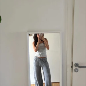 Grå mjukisbyxor från Scarlette M - Grå mjukisbyxor från Scarlette i storlek M. Byxorna har breda ben, resår i midjan med snörning och sidofickor. Sköna och loose fit, perfekta för chill dagar. Tillverkade i mjukt material som känns bekvämt mot huden.