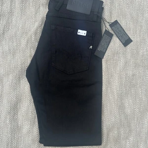 Svarta Replay rik jeans slim fit - Svarta jeans från Replay, modell rik, med slim fit-passform. Klassisk femficksdesign, diskret Replay-logga på bakfickan och svarta detaljer. Jeansen är tillverkade i stretchig bomullsblandning för en bekväm känsla och snygg siluett.