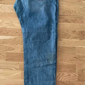 Blå slitna jeans från Iconic Sports - Säljer ett par blå jeans från Iconic Sports i storlek 38. Jeansen har en klassisk femficksmodell, slitna detaljer och ljus tvätt. De är raka i modellen och har snygga slitningar på benen för en avslappnad look.