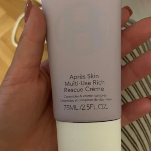 Après Skin Multi-Use Rich Rescue Crème - En multifunktionell ansiktskräm från Ole Henriksen med ceramider och vitamincomplex. Tuben är ljust lila med vitt lock och rymmer 75 ml. Perfekt för dig som vill boosta huden med fukt och näring. Enkel att ta med i väskan. helt ny