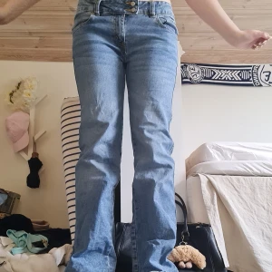 Blå lågmidjade jeans från 157 - Säljer ett par klassiska blå jeans från 157 med raka ben och normal passform. Jeansen har låg midja, fem fickor och stängs med dubbla knappar och dragkedja. Perfekta för dig som gillar en enkel och tidlös look. Materialet är jeans i bomull.