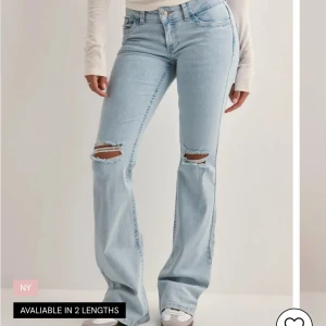 Ljusblå bootcut jeans med slitningar - Snygga ljusblå jeans med bootcut passform och slitna hål vid knäna. Jeansen har klassisk femficksdesign och coola broderade detaljer i rosa på bakfickorna. Perfekta för en avslappnad och trendig look.