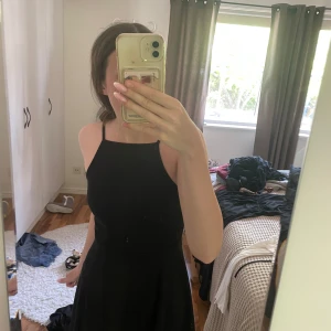 Svart kort klänning från FB Sister - Säljer en svart, enkel och stilren kort klänning från FB Sister. Klänningen har smala axelband och rak halsringning, sitter snyggt med en lätt utställd kjol. Perfekt för dig som gillar minimalistisk stil och vill ha något bekvämt och snyggt.