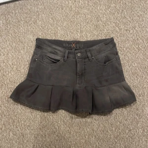 Svart jeanskjol med volang  - Snygg svart kortkjol i jeansmaterial från Dream Jeans by MAC. Står tyvärr ingen storlek men tror att den är ungefär xs- S. Midjemåttet är ungefär 78 cm