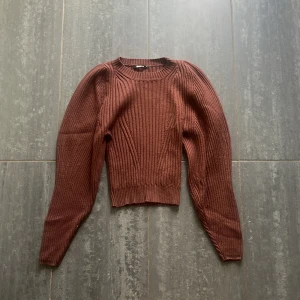 Brun ribbad stickad tröja Gina Tricot - Säljer en brun stickad tröja från Gina Tricot i storlek S. Tröjan har ribbat mönster, rund halsringning och långa puffärmar som ger en trendig siluett. 