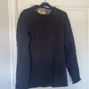 Mörkgrå stickad tröja Jack & Jones - Säljer en mörkgrå stickad tröja från Jack & Jones Originals. Tröjan har en snygg struktur med rutigt stickat mönster och rund halsringning. Perfekt för dig som gillar en enkel men stilren look. Långärmad och passar till många outfits.