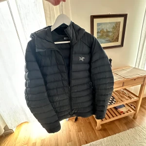 Mörkblå dunjacka Arc'teryx Cerium LT XL - 850 fill power dun | Lättvikt | Supervarm | Perfekt för lager-på-lager  Säljer min Arc’teryx Cerium LT dunjacka med luva – en av de mest eftertraktade lättviktsdunjackorna på marknaden. Extremt lätt och komprimerbar, men ändå varm tack vare 850 fill power gåsdun + syntetisolering där det behövs. Jackan har lagats av sömmerska för en skada men Inget dun som läcker ut, se bild. Nypris cirka 4000 kr