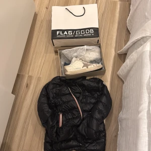 Golden Goose vita sneakers med stjärna och moncler  - Golden Goose sneakers i vitt skinn med den ikoniska grå stjärnan på sidan. Skorna har grå snörning, platt sula och en vintage-inspirerad look. Perfekta för dig som gillar en avslappnad och trendig stil. Moncler för 12 år 