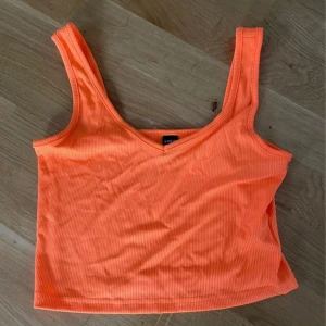 Ribbad orange croppad linne från SHEIN - Superfräsch croppad linne i stark orange färg från SHEIN. Toppen är ribbad med v-ringning och breda axelband, perfekt för varma dagar. Snygg och enkel att matcha med jeans eller kjol för en cool look.