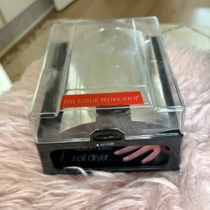 The Color Workshop nageltork - Elektrisk nageltork från The Color Workshop i svart och transparent plast. Har en on/off-knapp framtill och plats för att torka naglarna snabbt och smidigt. Perfekt för dig som älskar att fixa naglarna hemma.
