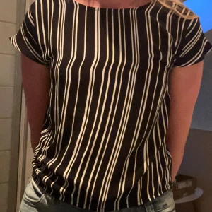 Svartvit randig blus från Lindex - Snygg svart blus från Lindex med vita vertikala ränder. Modellen är lös med korta ärmar och rund halsringning. Tunt och lätt material som känns skönt mot huden. Passar även till folk som bär xs/s i vanliga fall!💗💕Pris kan diskuteras!