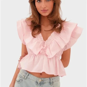 Ljusrosa volangtopp med v-ringning - Supersöt ljusrosa blus med volanger med v-ringning. Perfekt att styla med jeans eller kjol för en trendig look. Den är i storlek xxs/xs och helt ny. Den har kvar prislappen. Det är bara att skriva ifall man vill ha fler bilder på den💞 