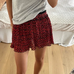 Kjol - Superfin kort plisserad kjol från Retour med rött leopardmönster/ pussmunnar 💋 Resårmidja med ränder i svart, vitt och rött samt en cool stjärna framtill. Går att justera längd! 