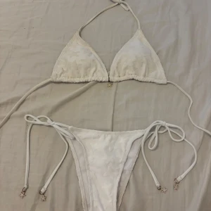 Vit triangel bikini med sjöstjärnor  - Superfin vit bikini med ”fluffiga” sjöstjärnor och små guldfärgade sjöstjärneberlocker på snörena. Triangeltopp med knyt i nacken och ryggen samt matchande underdel med knyt i sidorna. Aldrig använd. ☀️❤️