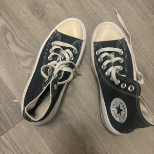 Svarta Converse All Star sneakers - Klassiska svarta Converse All Star sneakers med vit sula och tå, vita snören och det ikoniska logotypmärket på sidan. Skorna har rund tå och är tillverkade i canvas med kontrasterande sömmar. Perfekta för en avslappnad och cool stil.