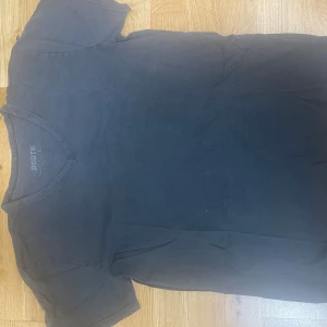 Svart v-ringad t-shirt från Dcore - En svart t-shirt från Dcore med v-ringning och korta ärmar. Enkel och stilren design som passar till det mesta. Tillverkad i mjuk bomull för skön känsla hela dagen.