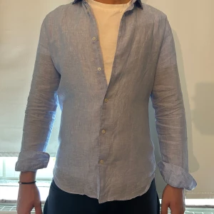 Ljusblå linneskjorta från  - Tja, säljer nu min skjorta från Riley som nu är lite för liten. Jag är ända ägaren och tycker själv att den är i väldigt bra skick men det får du bedöma själv. Modellen är 185cm lång så skulle säga att skjortan passar någon som är 170-180. Hör av dig ifall du har några frågor eller vill ha fler bilder.    MVH Alfred 