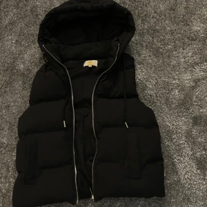 Svart väst med huva från Chelsea - Säljer en svart dunväst från Chelsea i storlek S🌟