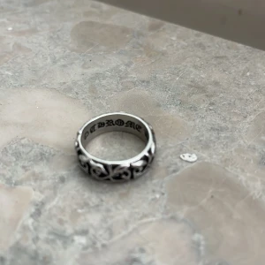 Chrome Hearts silverring med gravyr - silverring från Chrome Hearts med detaljerat, snirkligt mönster runt hela ringen. På insidan finns gravyr med texten 'CHROME HEARTS 2000'.