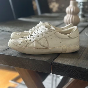 Vita sneakers från Philippe Model - Snygga vita sneakers från Philippe model. Skorna har snörning och är tillverkade i skinn med diskreta detaljer på sidan och logga på hälen. Perfekta för en clean och stilren look.